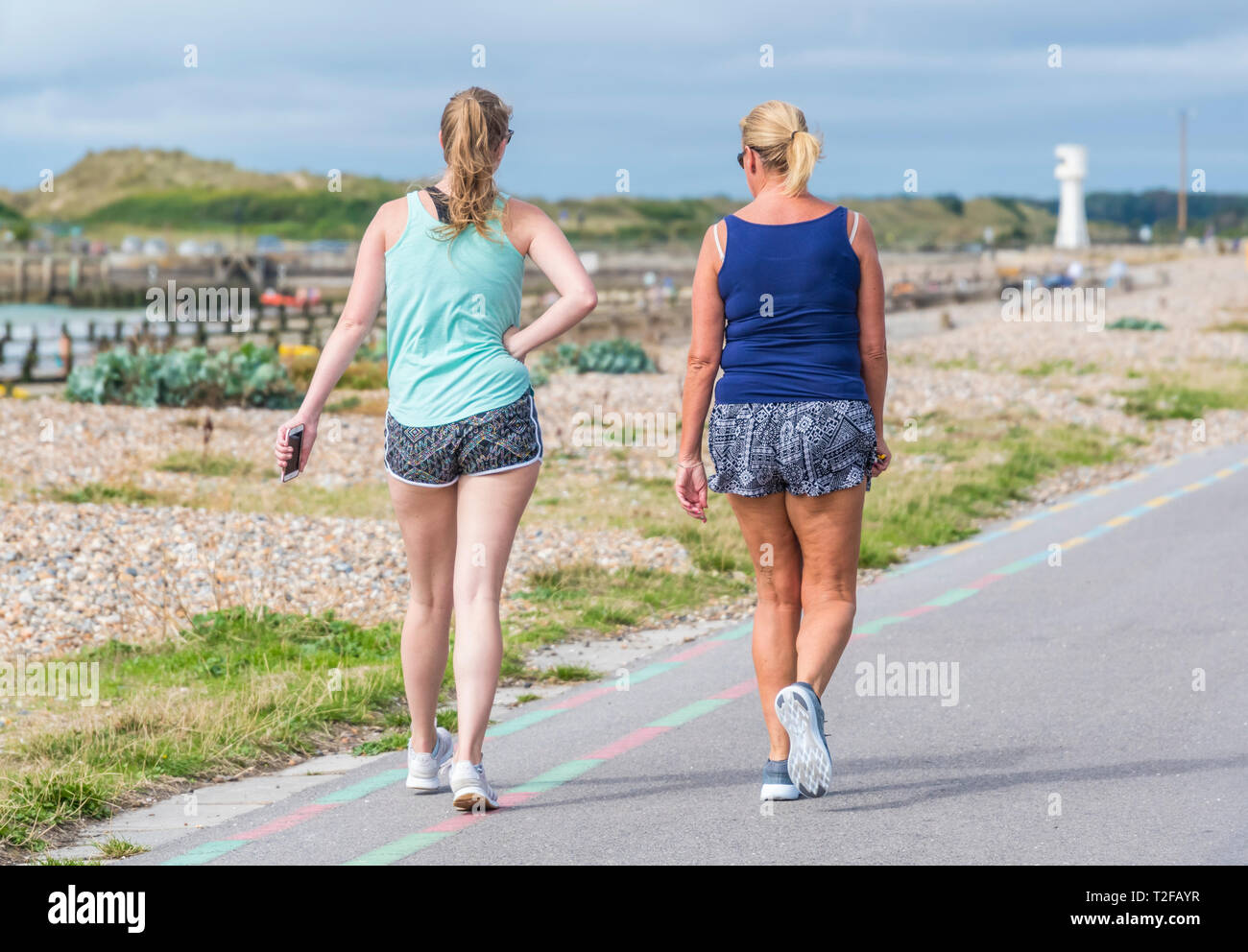 Coppia di donne a piedi lungo la passeggiata sul lungomare in estate nel Regno Unito. Foto Stock