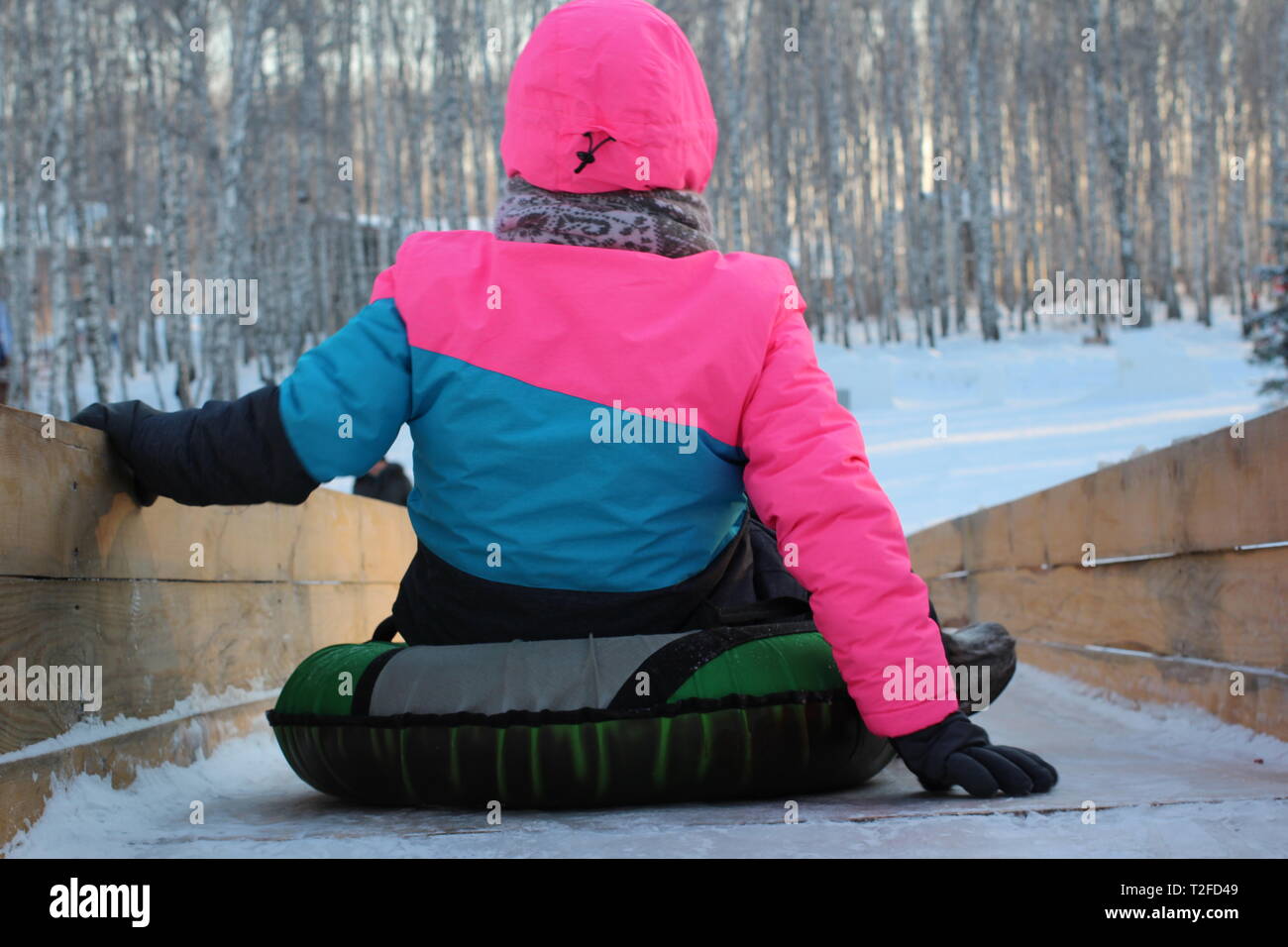 La ragazza preparati a rotolare giù per la diapositiva di ghiaccio in inverno su una slitta gonfiabile Foto Stock