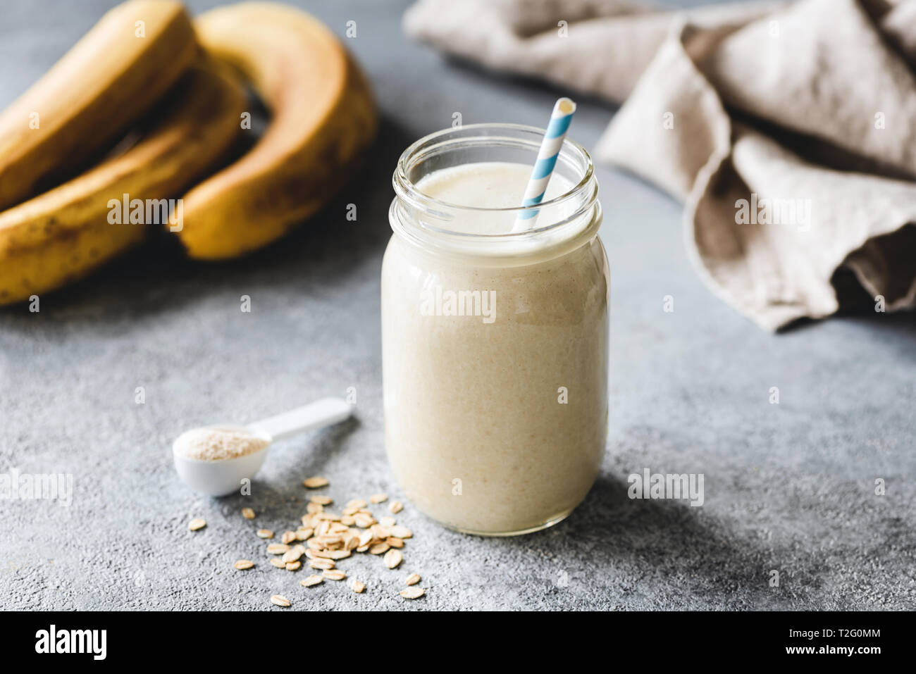 Proteina frullato di banane in barattolo, proteina scoop, avena e lino tessile sulla tabella. Una sana Vegana Vegetariana o bevande per sportivi Foto Stock