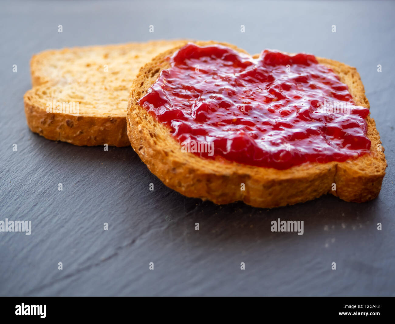 Due Fette Di Pane Tostato Con Marmellata Di Lamponi Su Una Piastra Di Ardesia Foto Stock Alamy