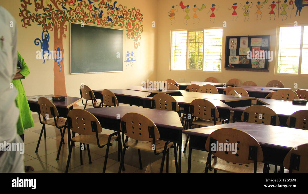 Scuola d'arte con tavoli e sedie con arte e disegni sulla parete a scuola Foto Stock