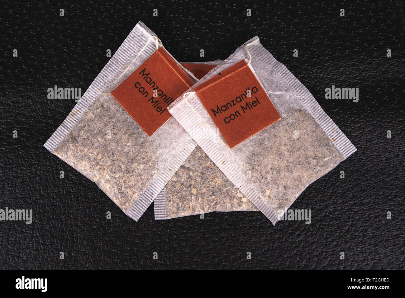 Tre sacchetti con tè camomilla interno e marrone con etichetta ogni, su una superficie di colore nero Foto Stock