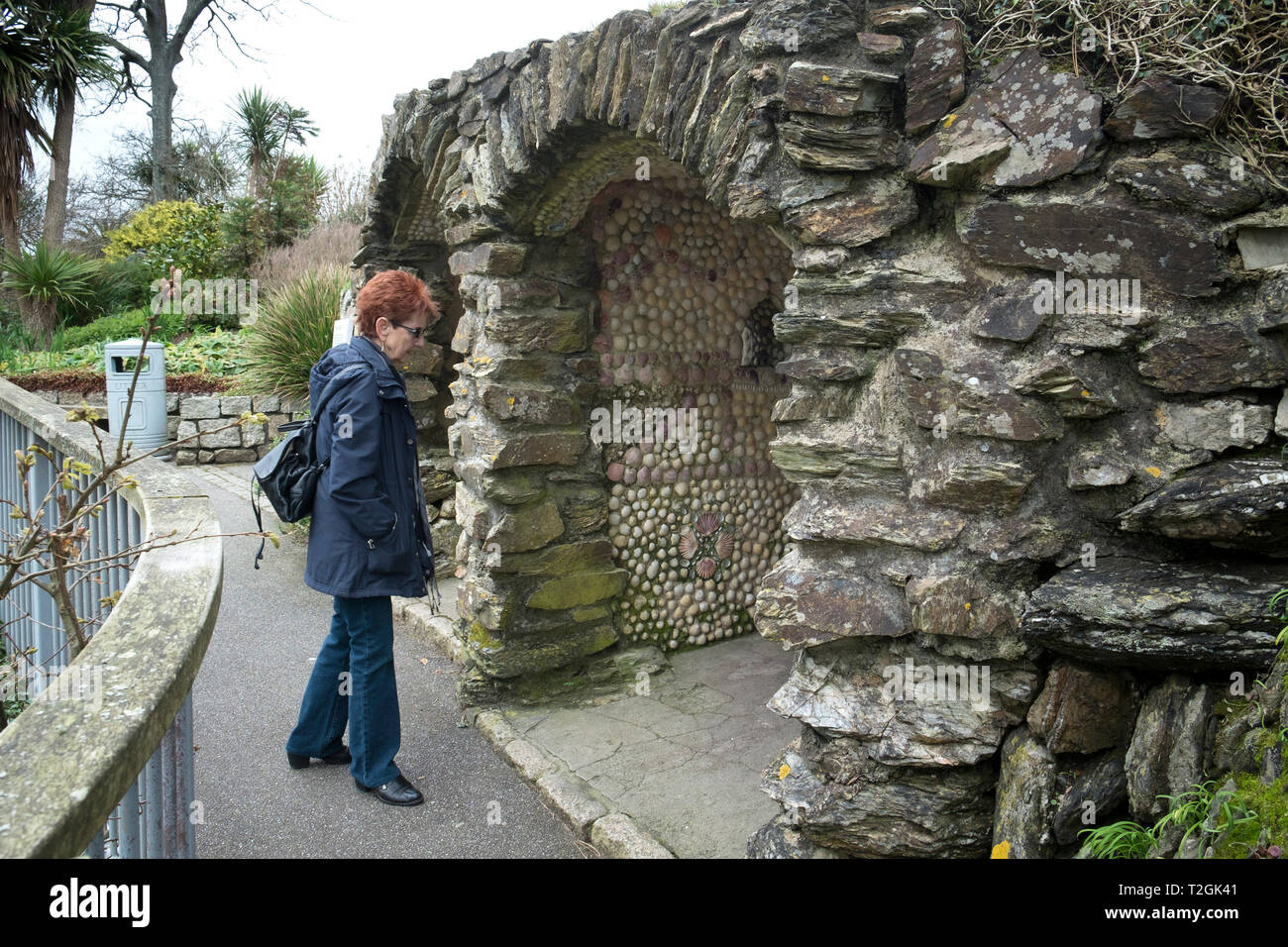 Un visitatore guardando la storica restaurata sedili a guscio in Gyllyngdune Giardini in Falmouth in Cornovaglia. Foto Stock