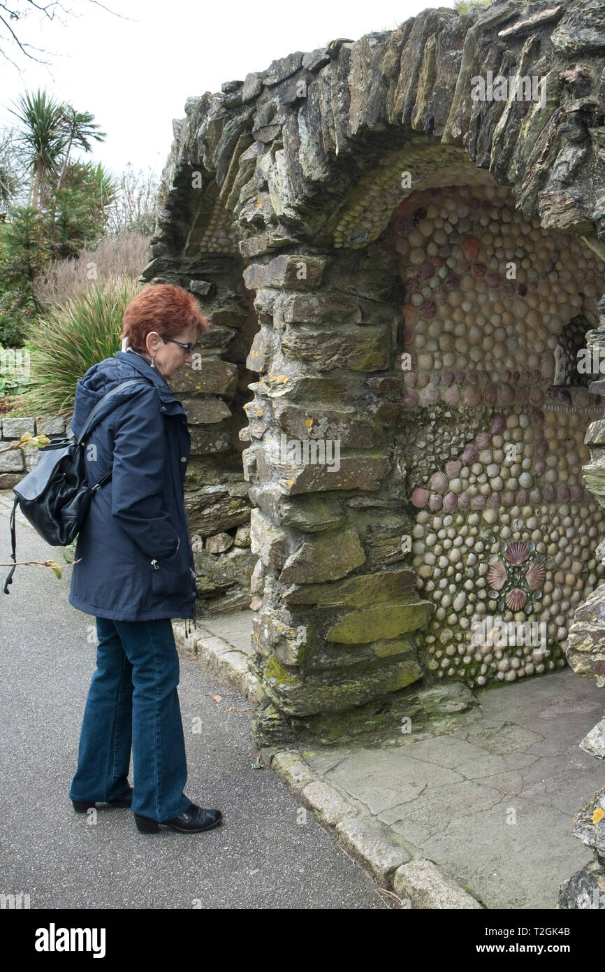 Un turista guardando la storica restaurata sedili a guscio in Gyllyngdune Giardini in Falmouth in Cornovaglia. Foto Stock
