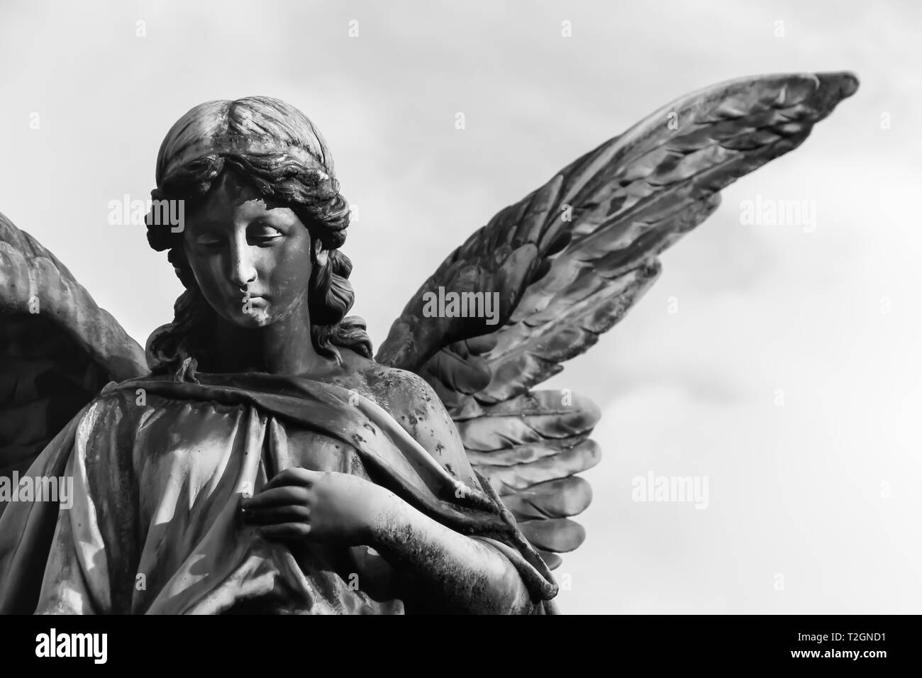 Triste Angelo Scultura Con Open Ali Lunghe Attraverso Il Telaio Contro Un Bianco Luminoso Cielo L Espressione Triste Scultura Con Gli Occhi Verso Il Basso E Il Lato Di Fronte Foto Stock