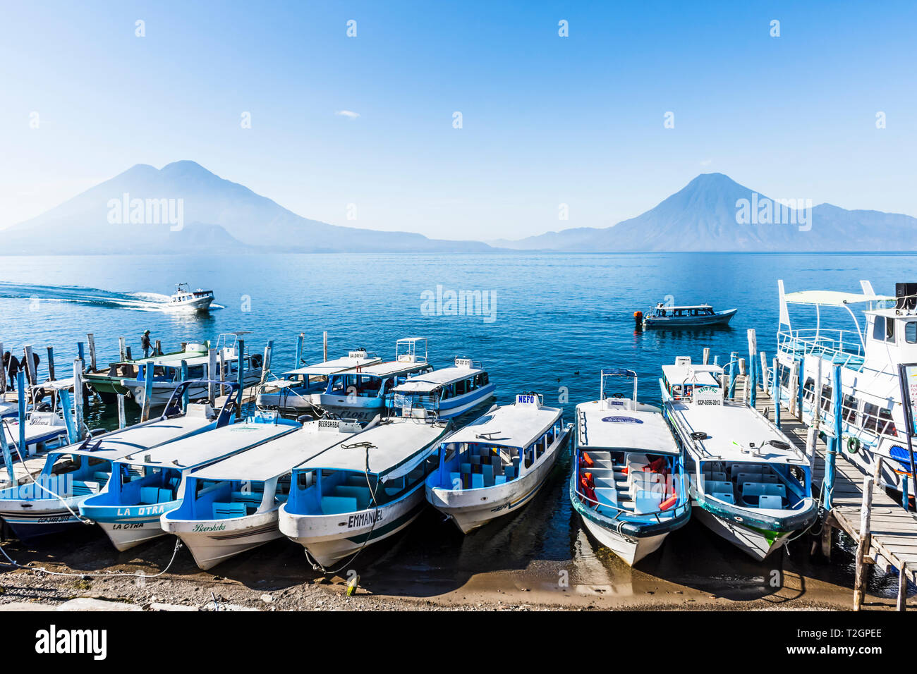 Panajachel, lago Atitlan, Guatemala - 23 dicembre 2018: barche tirate fino alla spiaggia con Toliman, Atitlan & San Pedro vulcani sull orizzonte in Panajachel Foto Stock