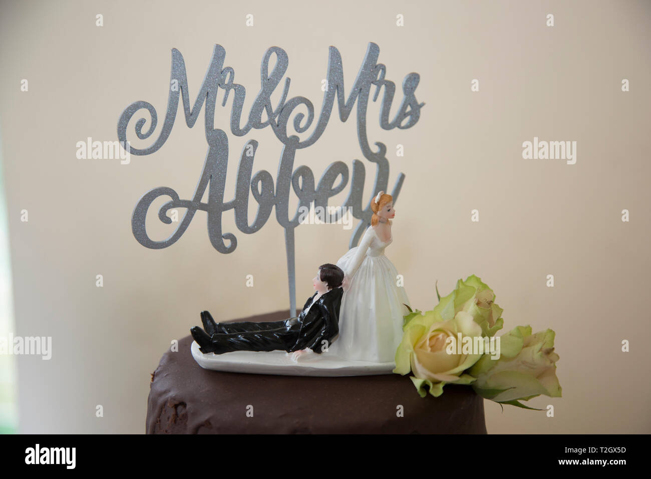 Cioccolato torta di nozze con divertenti cake topper della sposa sposo di trascinamento lungo dal suo collare Foto Stock