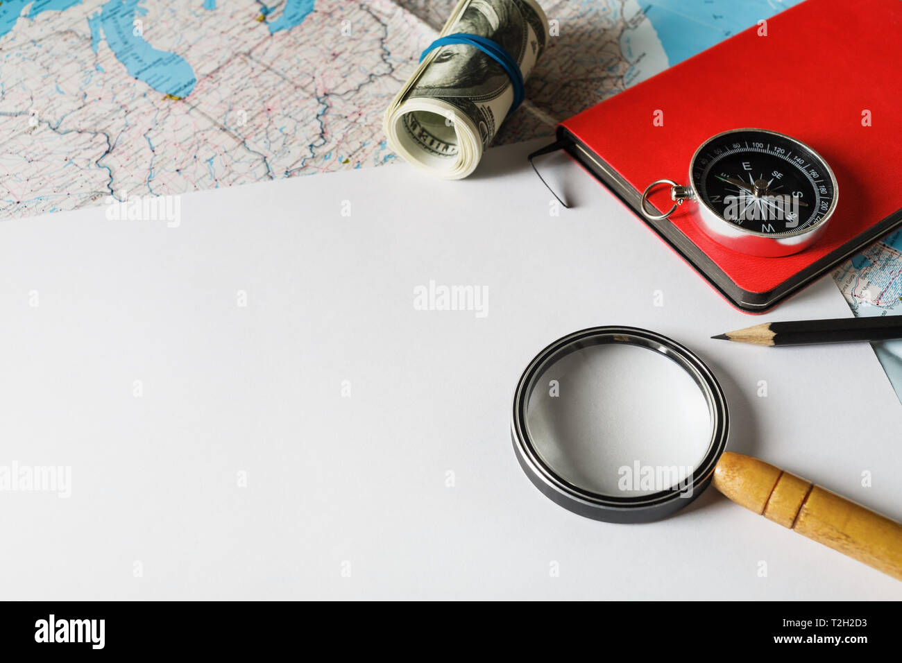 Piano di viaggio sfondo. magnifier, bussola, denaro, notebook e matita su carta bianca dello sfondo. Foto Stock