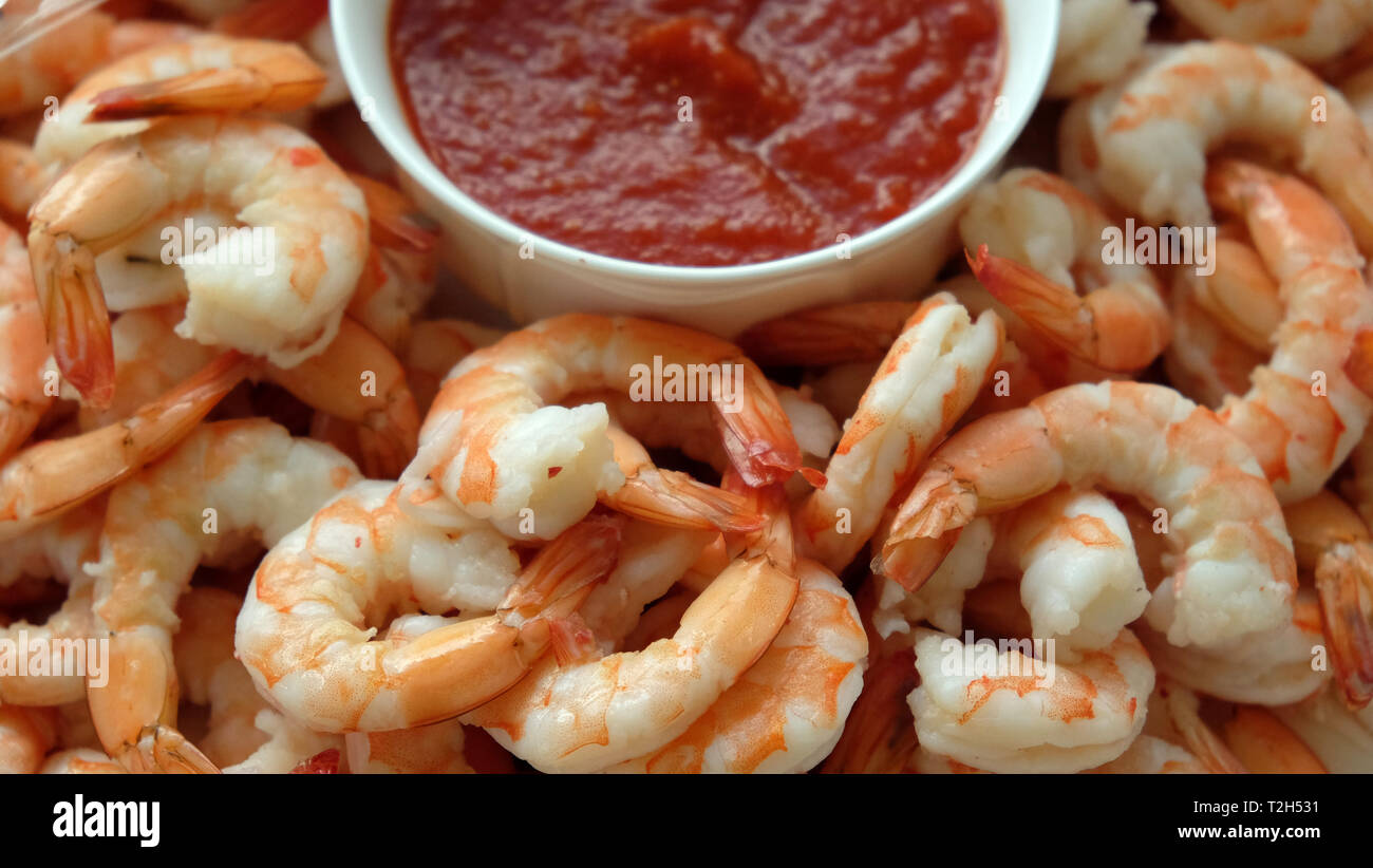 Una piastra di gamberi freschi con una ciotola di salsa cocktail Foto Stock