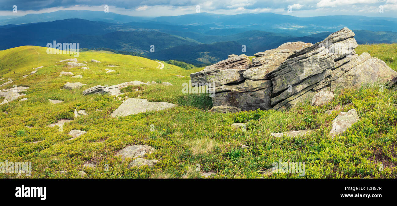 Scenario di mattina in montagna. meraviglioso paesaggio estivo con rocce sulle colline erbose. coperto il cielo sopra la cresta distanti Foto Stock