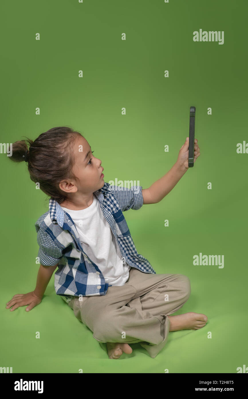 Un simpatico capelli lunghi boy selfie con il suo mobile su sfondo verde Foto Stock