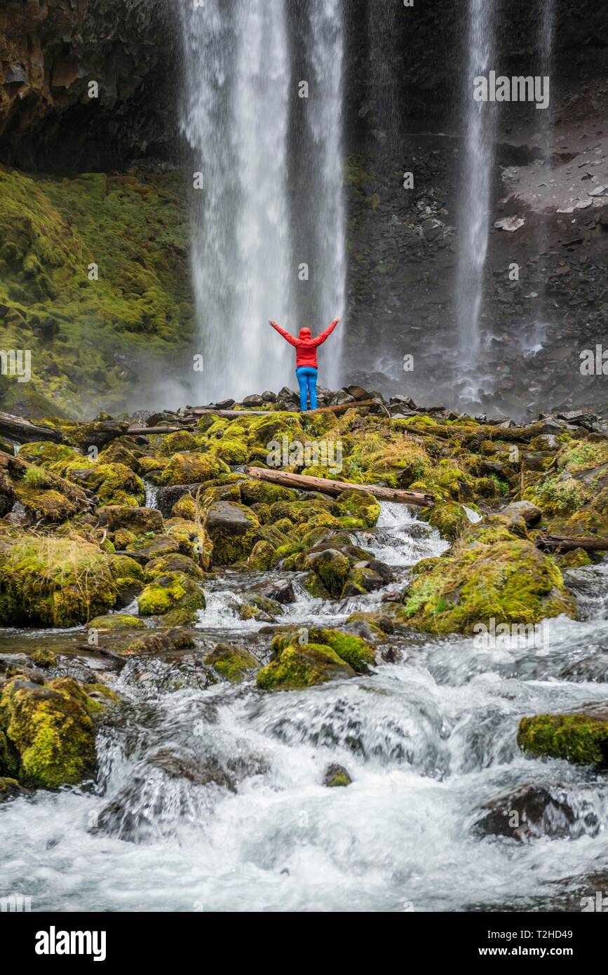 Escursionista con bracci sollevata davanti ad una alta cascata, acqua cade su un promontorio roccioso, Tamanawas cade, il fiume selvaggio Cold Spring Creek, Oregon, Stati Uniti d'America Foto Stock
