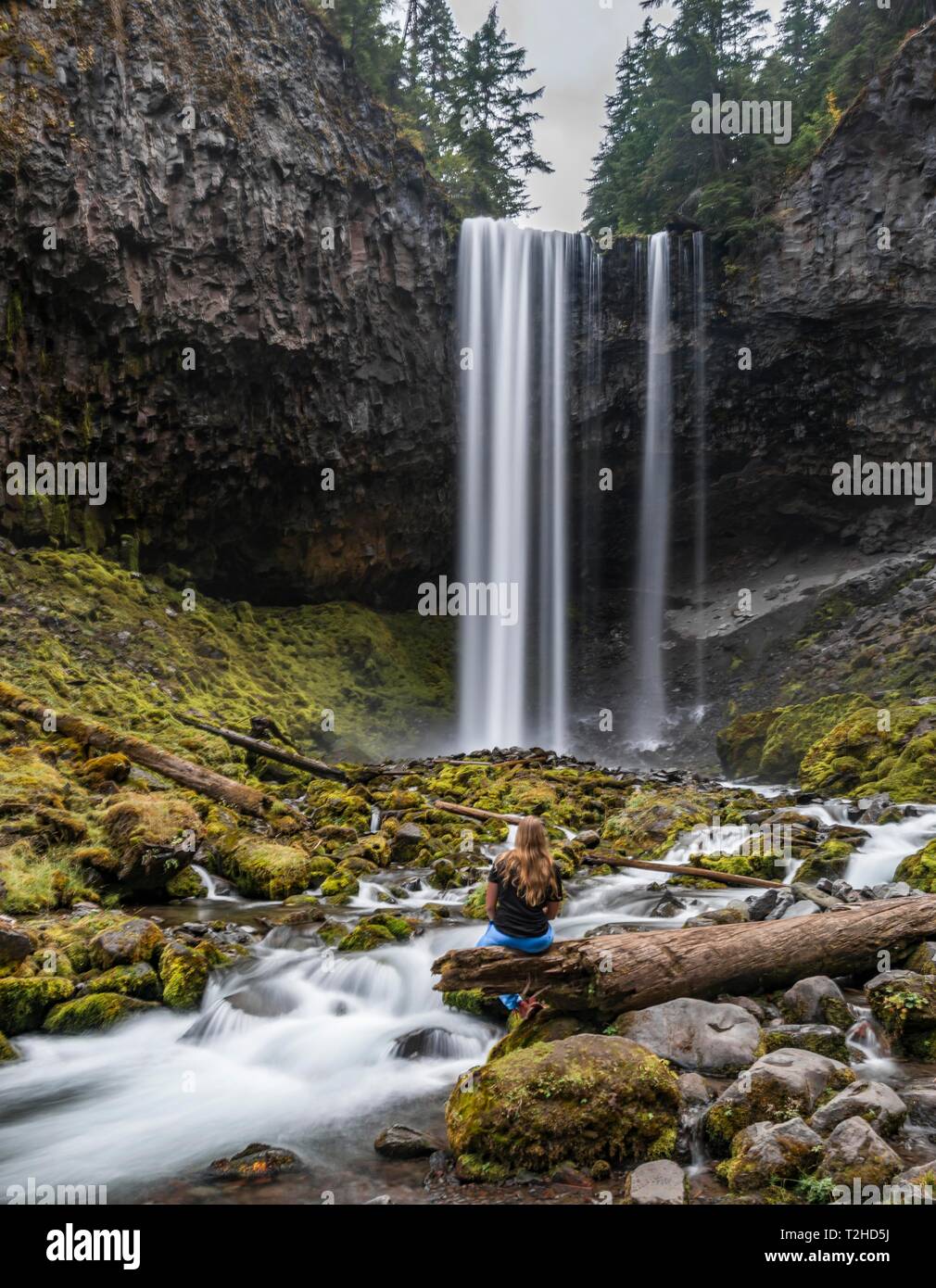 Giovane donna seduta a un fiume, escursionista cascata sprofondare verso il basso di una rupe, tempo di esposizione, fiume Cold Spring Creek, Tamanawas Falls, Oregon, Stati Uniti d'America Foto Stock