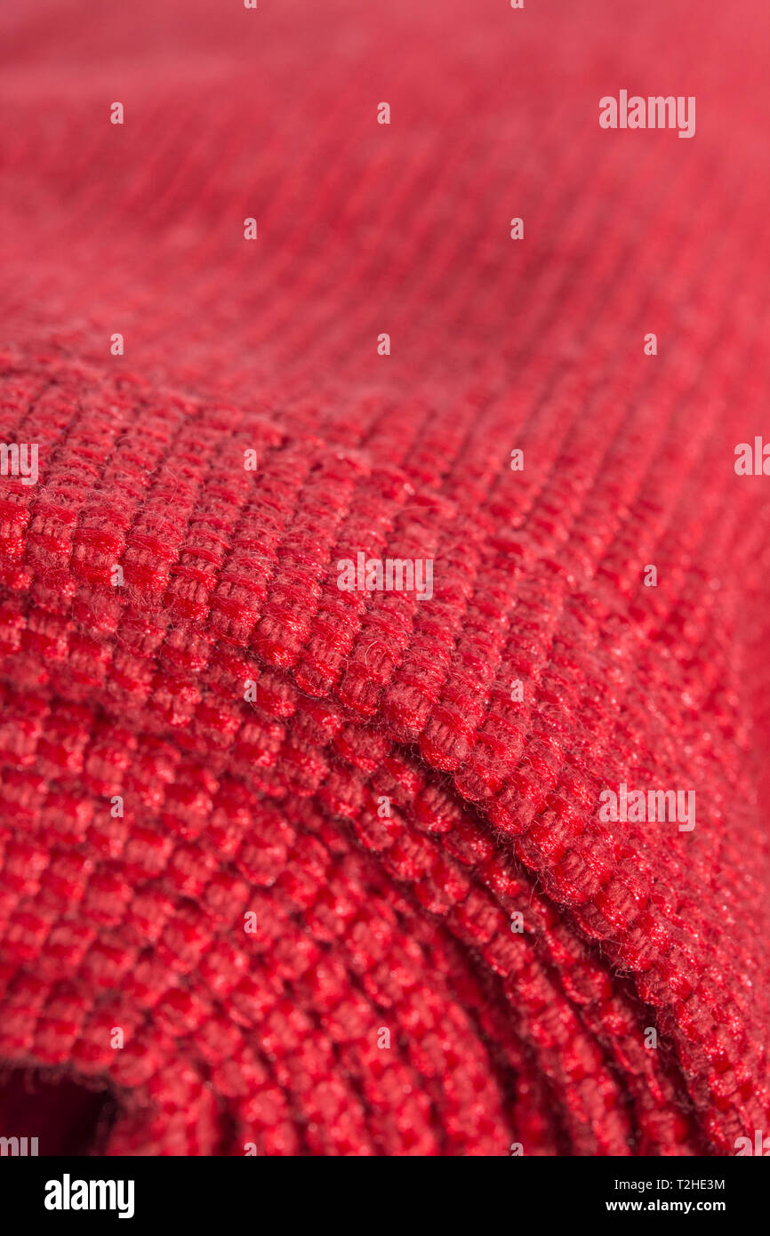 Close-up / macro estreme di orange materiale in poliestere con red cucitura. Metafora arrotolato su un rullo, tessuto bordo. Foto Stock