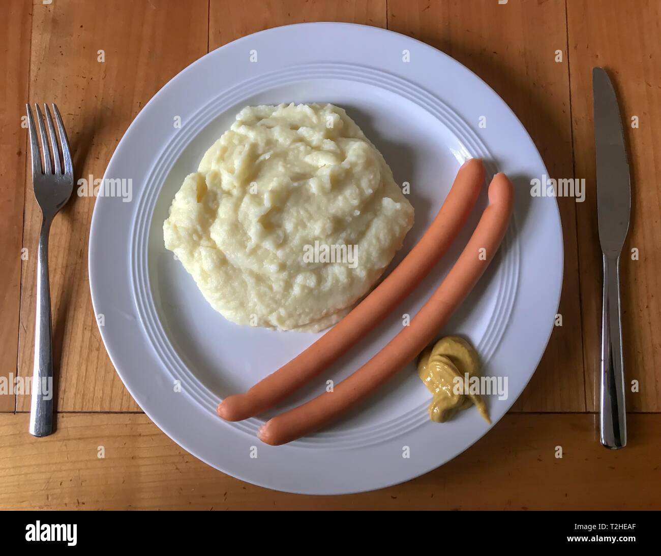 La salsiccia con purè di patate e senape sulla piastra con posate, tavolo in legno, Germania Foto Stock