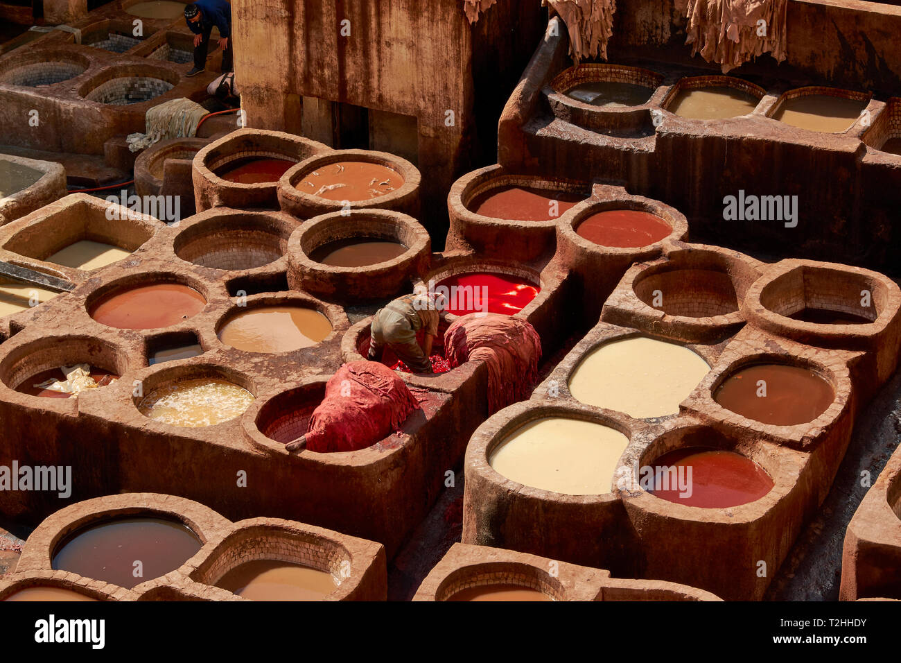 Il Marocco Fes Medina La conceria CHOUARA nasconde in vasche con pigmenti colorati e un lavoratore in un ordinamento IVA IL CUOIO Foto Stock