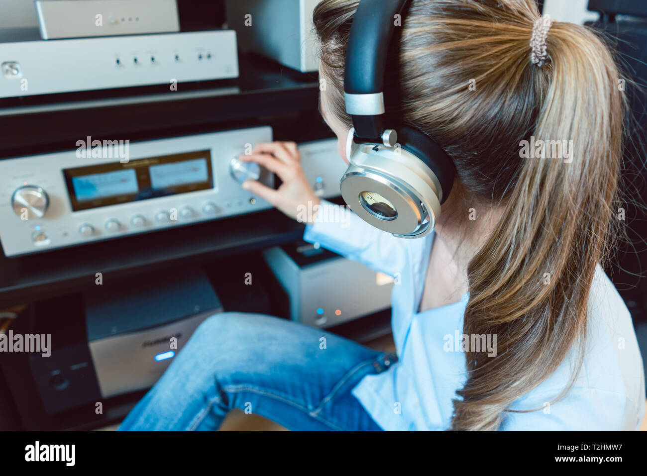 Donna con cuffie per ascoltare musica tramite l'impianto stereo hi-fi in  casa sua Foto stock - Alamy