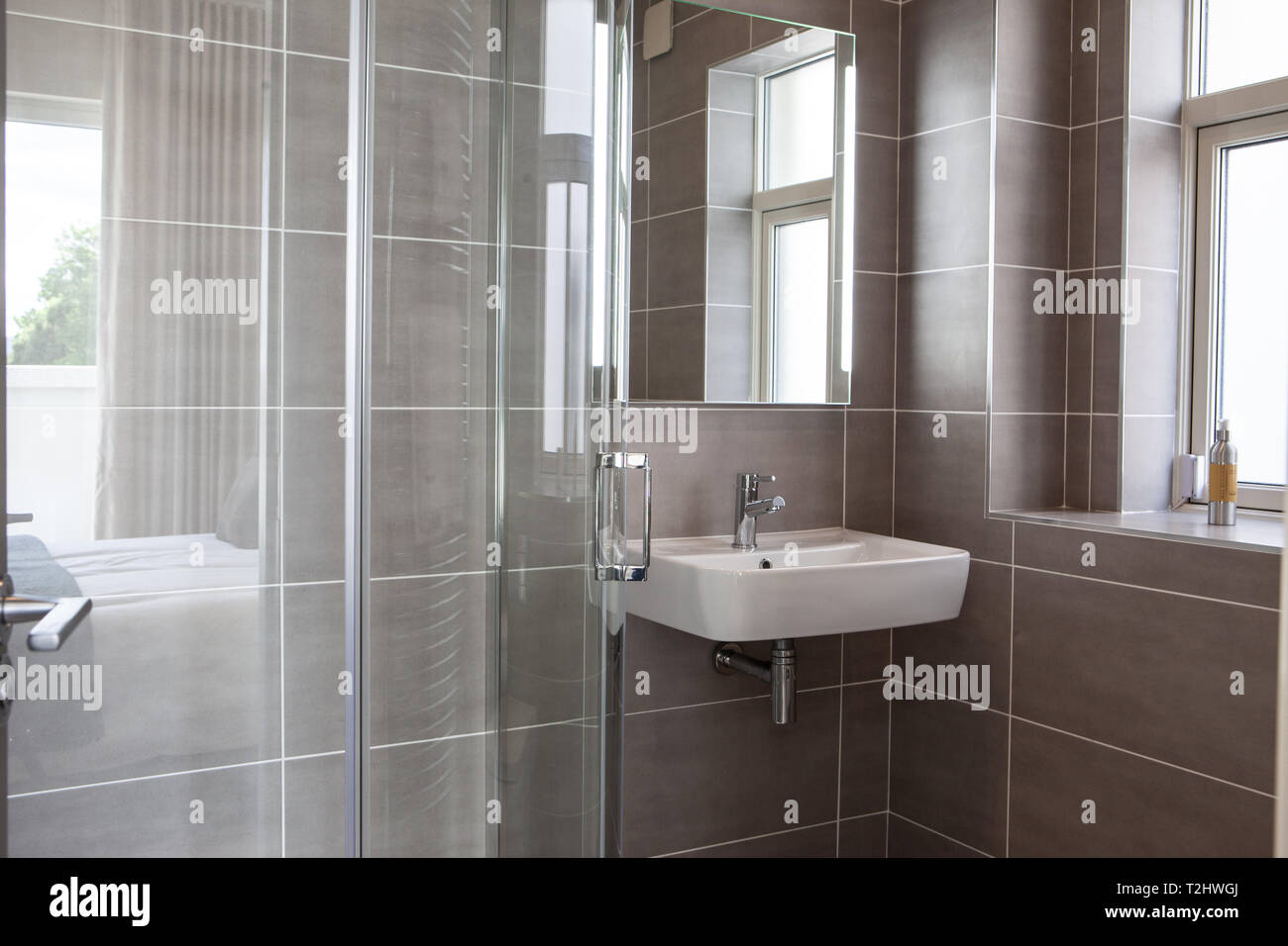Una moderna stanza da bagno con lavandino fixture e cabina doccia con porta in vetro Foto Stock