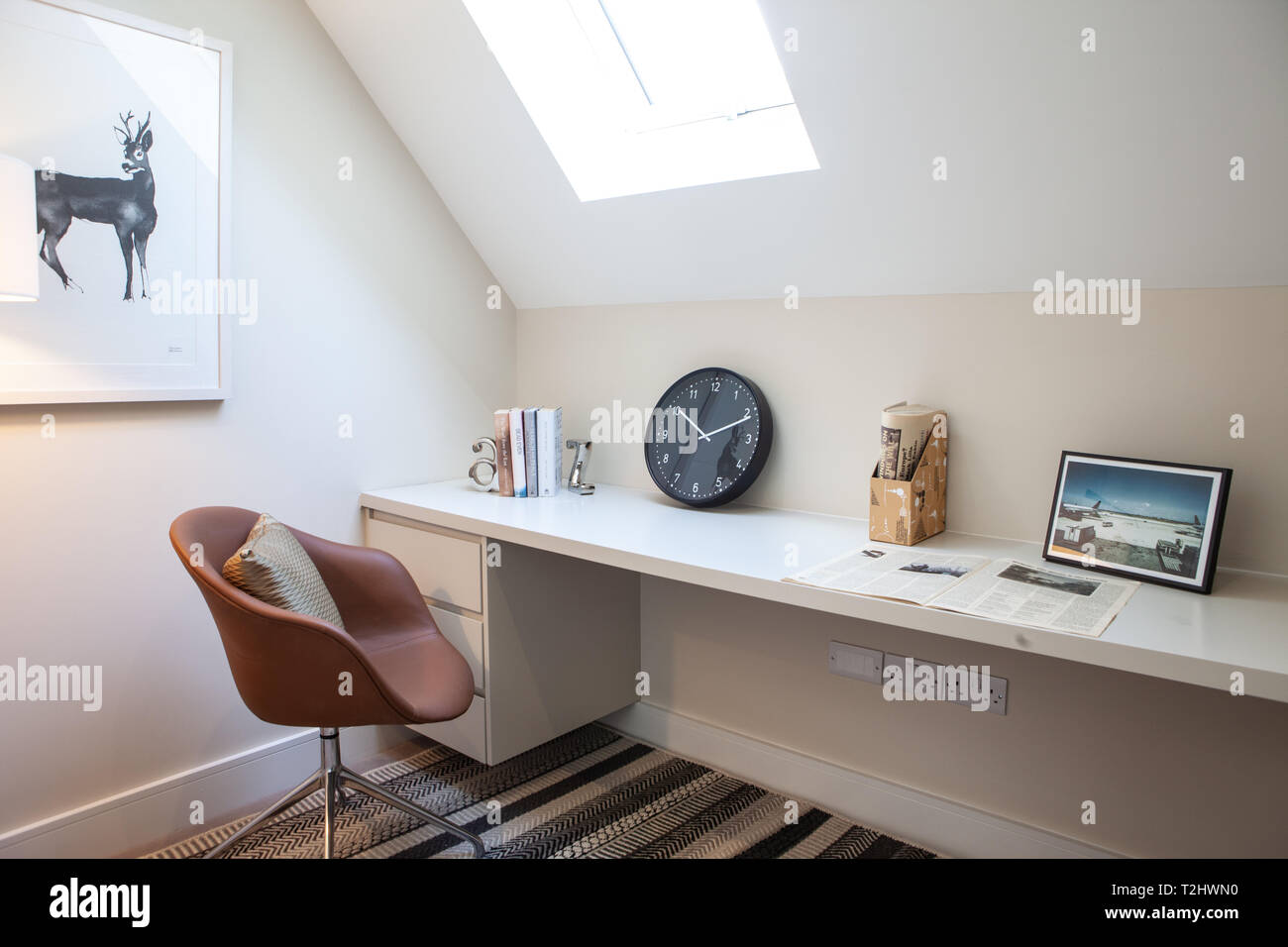 Modern home office layout in una casa mostra con una scrivania, sedia e la parete di immagine e lucernario o finestra velux a soffitto Foto Stock