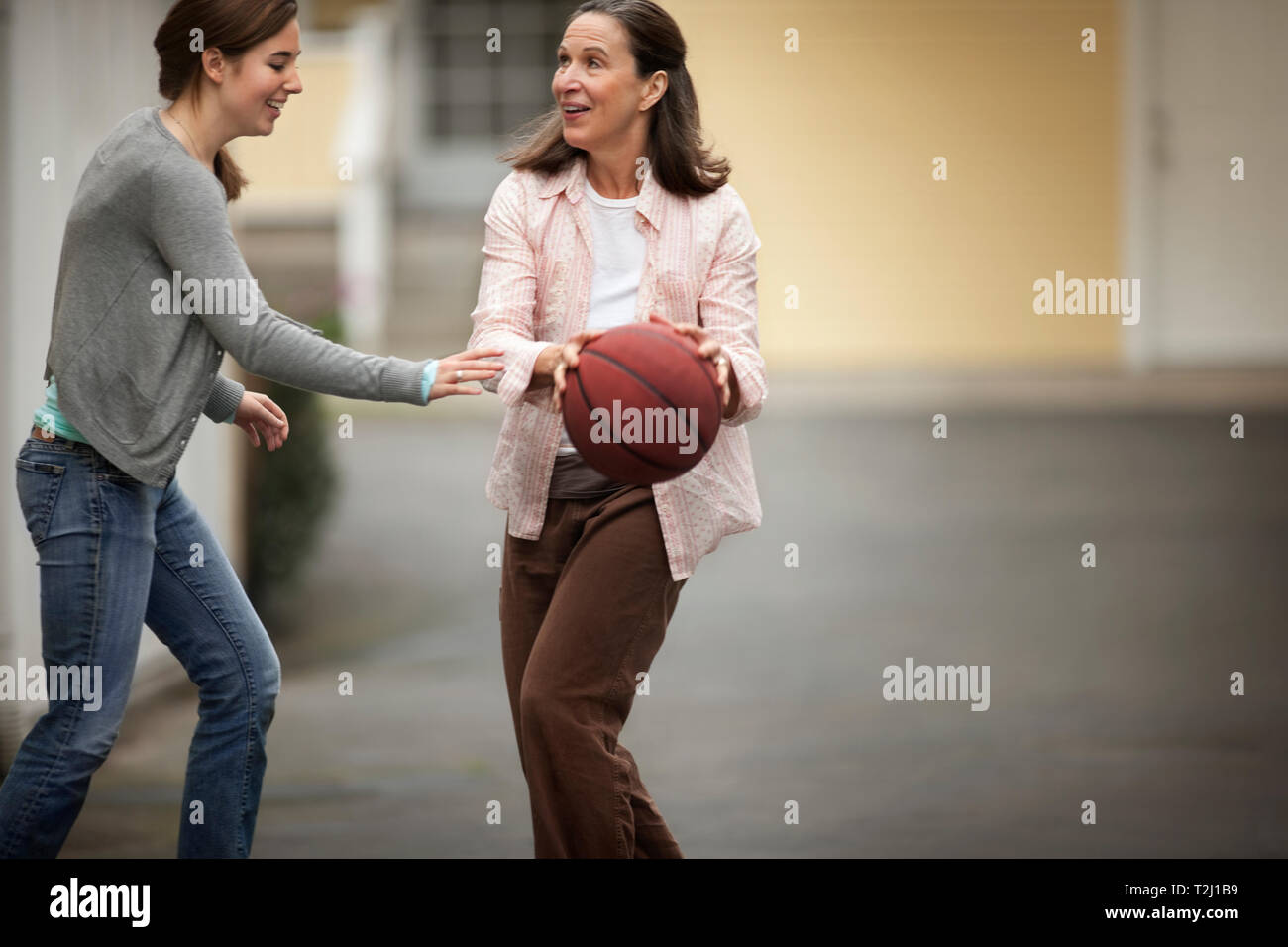 Felice madre e figlia giocare a basket sulla loro vialetto. Foto Stock