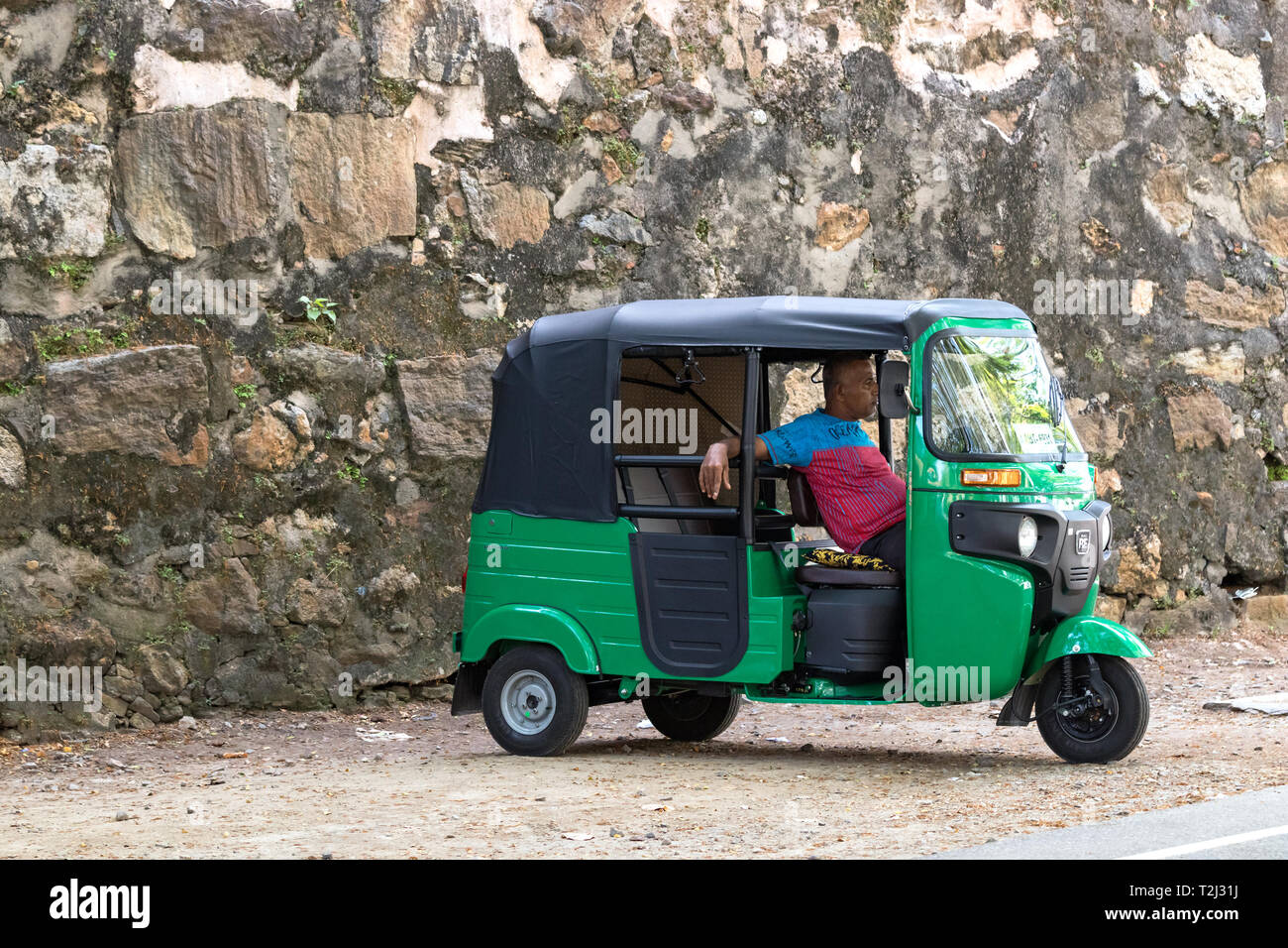 Galle, Sri Lanka - Febbraio 18th, 2019: un tuk tuk driver in attesa di passeggeri parcheggiato a Matara Road a Galle, Sri Lanka. Foto Stock