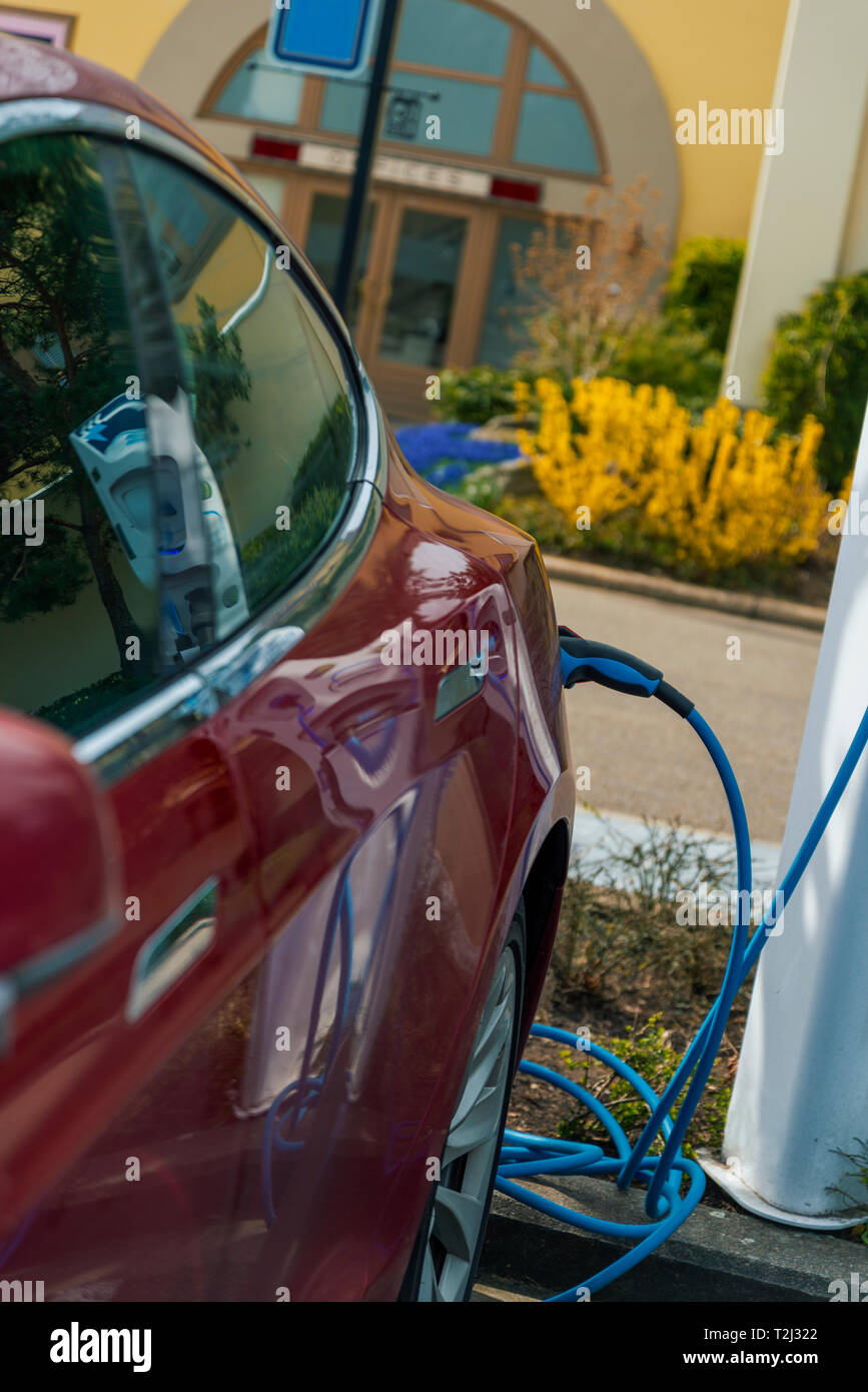 Auto elettrico collegato ad un polo di ricarica. concetto per la consapevolezza ambientale. Foto Stock