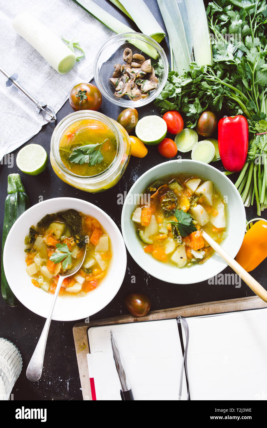 Il Minestrone ricetta, degustazione e la scrittura rcipe sul libro di cucina di italiano per il minestrone, sulla ciotola e jar con pomodoro ciliegino brown, calce e link roun Foto Stock