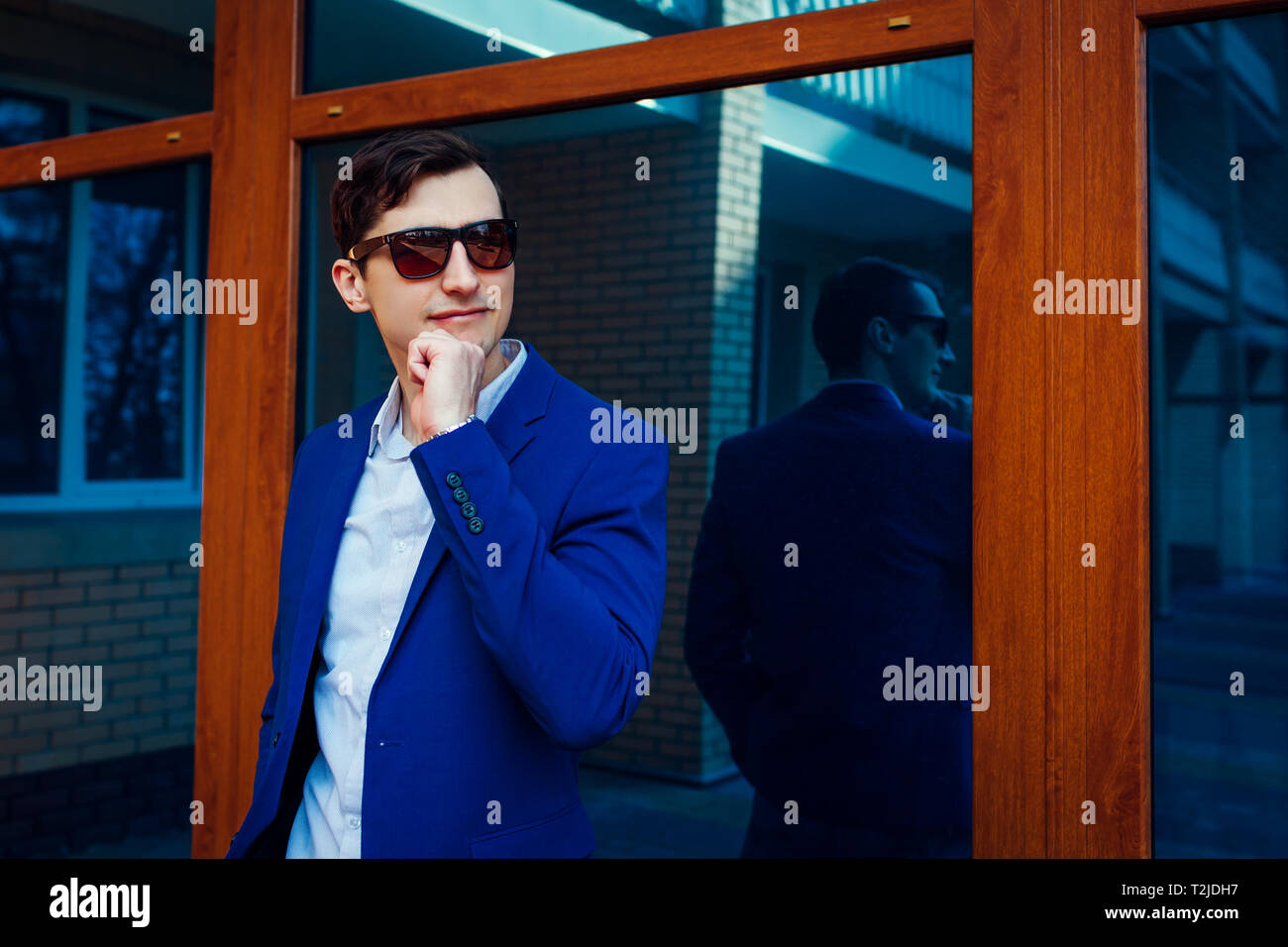 Felice giovane elegante uomo a camminare in città. Bel ragazzo indossa abiti classici e accessori. Spring street fashion. Foto Stock