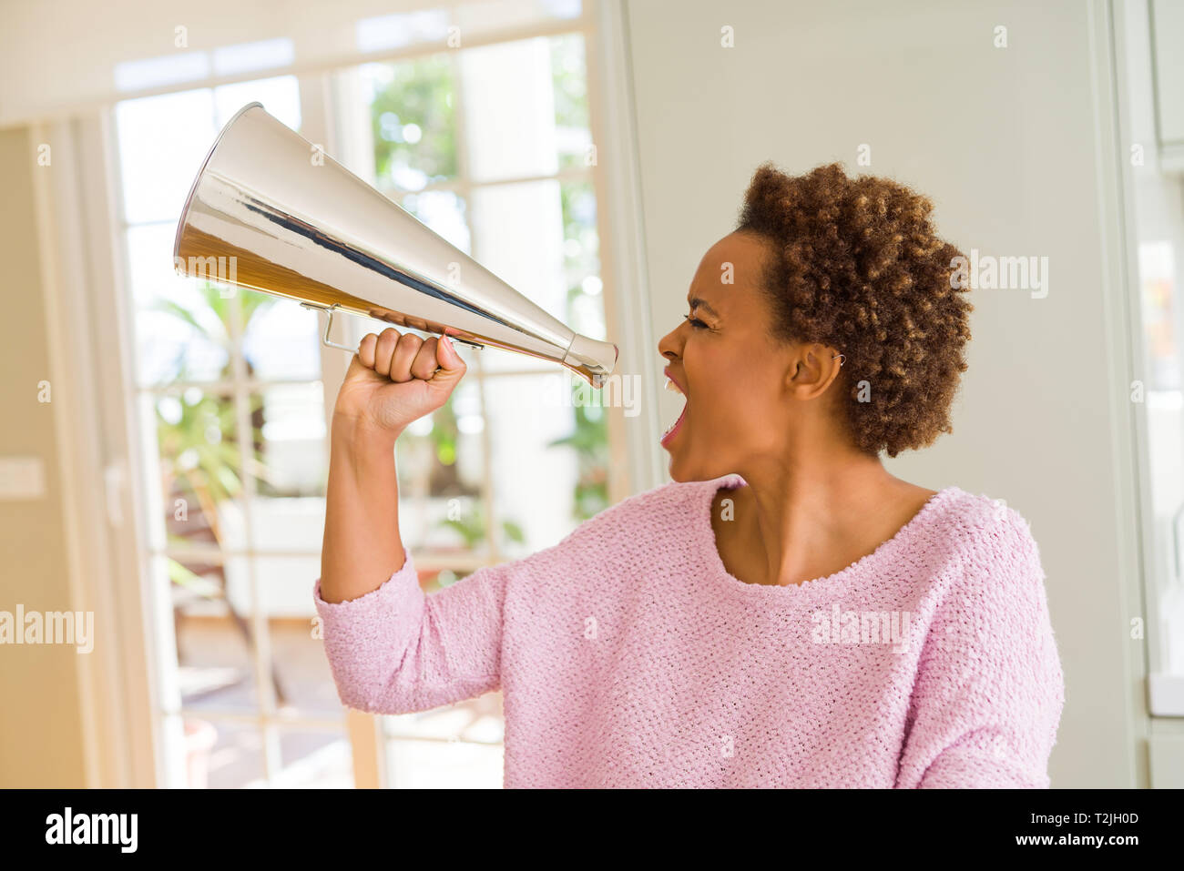 Giovani belle americano africano donna con capelli afro urlando utilizzando megafono Foto Stock