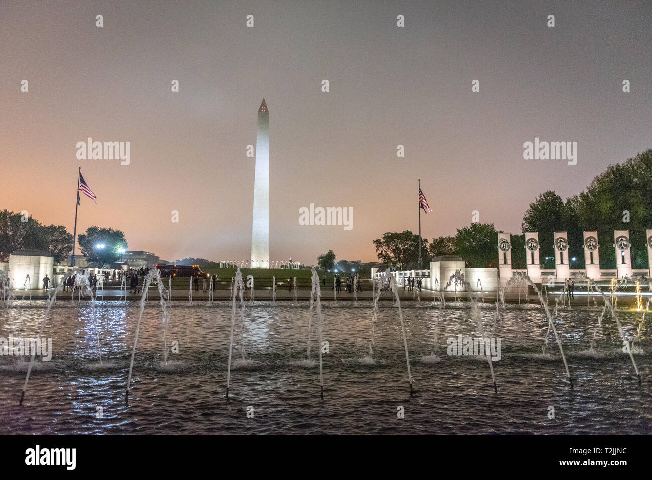 Cieli notturni glow arancioni su National Memoriale della Seconda Guerra Mondiale con il Monumento a Washington in aumento nella distanza, Washington, D.C. Foto Stock