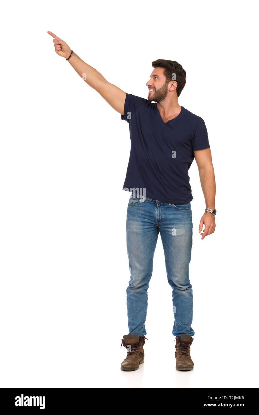 Bel uomo in jeans, stivali e blu t-shirt è in piedi rivolto verso l'alto e  mostrando qualcosa. Lunghezza completa studio shot isolato su bianco Foto  stock - Alamy