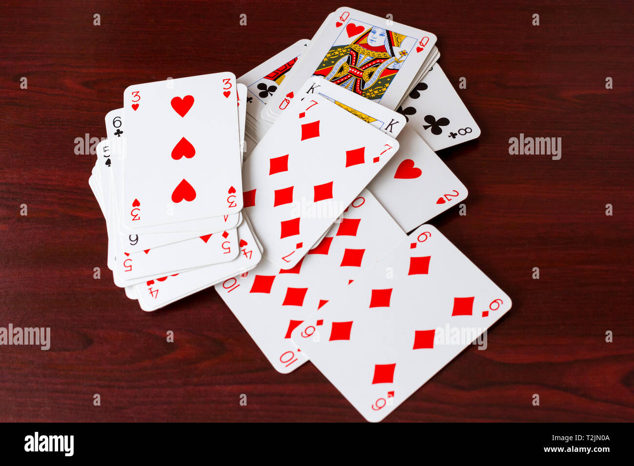 Alcune carte da gioco sparsi su di un legno scuro tabella Foto Stock