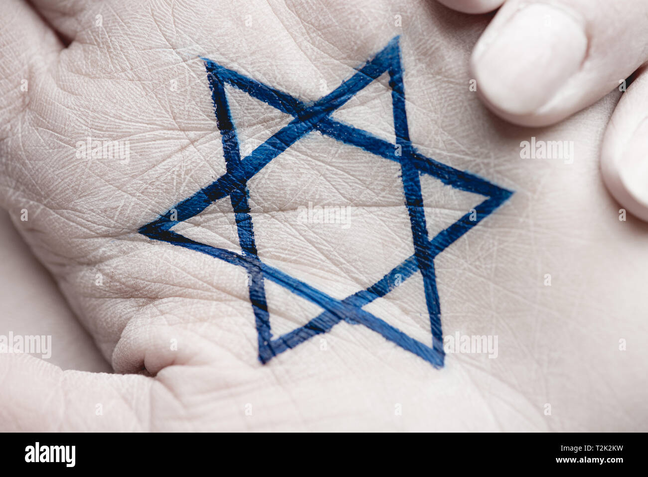 Close up di mani femminili con stella ebraica di Davide su grigio Foto Stock