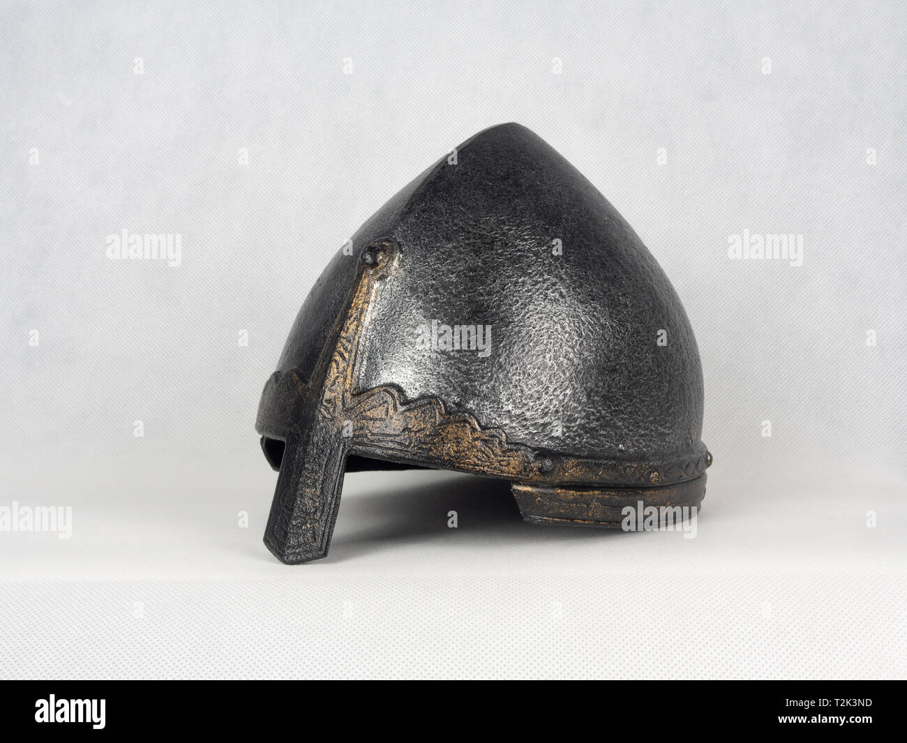 Inizio metallo medievale cavaliere del casco. Casco con protezione naso e templi decorati con ornamenti su uno sfondo bianco. Foto Stock