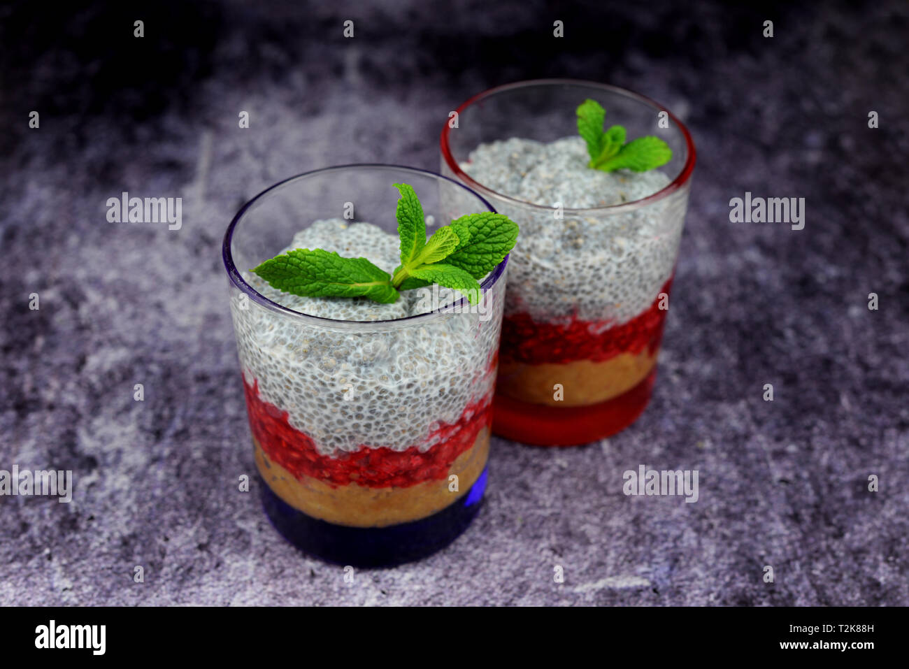 Chia il grano con il latte dolce con lampone e fragola berry il riempimento in bicchieri di vetro con foglia di menta Foto Stock