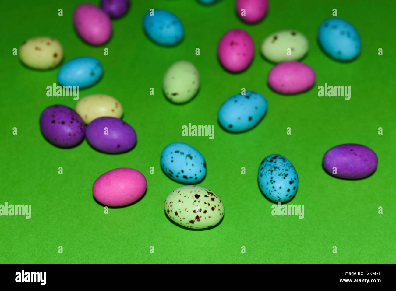 Sparse screziato Candy le uova sulla superficie verde Foto Stock