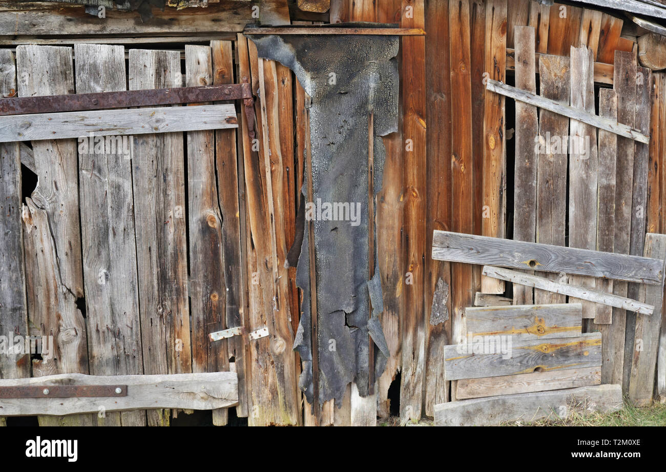 Al solito marcio in legno curvato parete vintage rurale del capannone per il deposito di legna da ardere e attrezzi agricoli. Collage panoramico da diversi colpi esterni Foto Stock