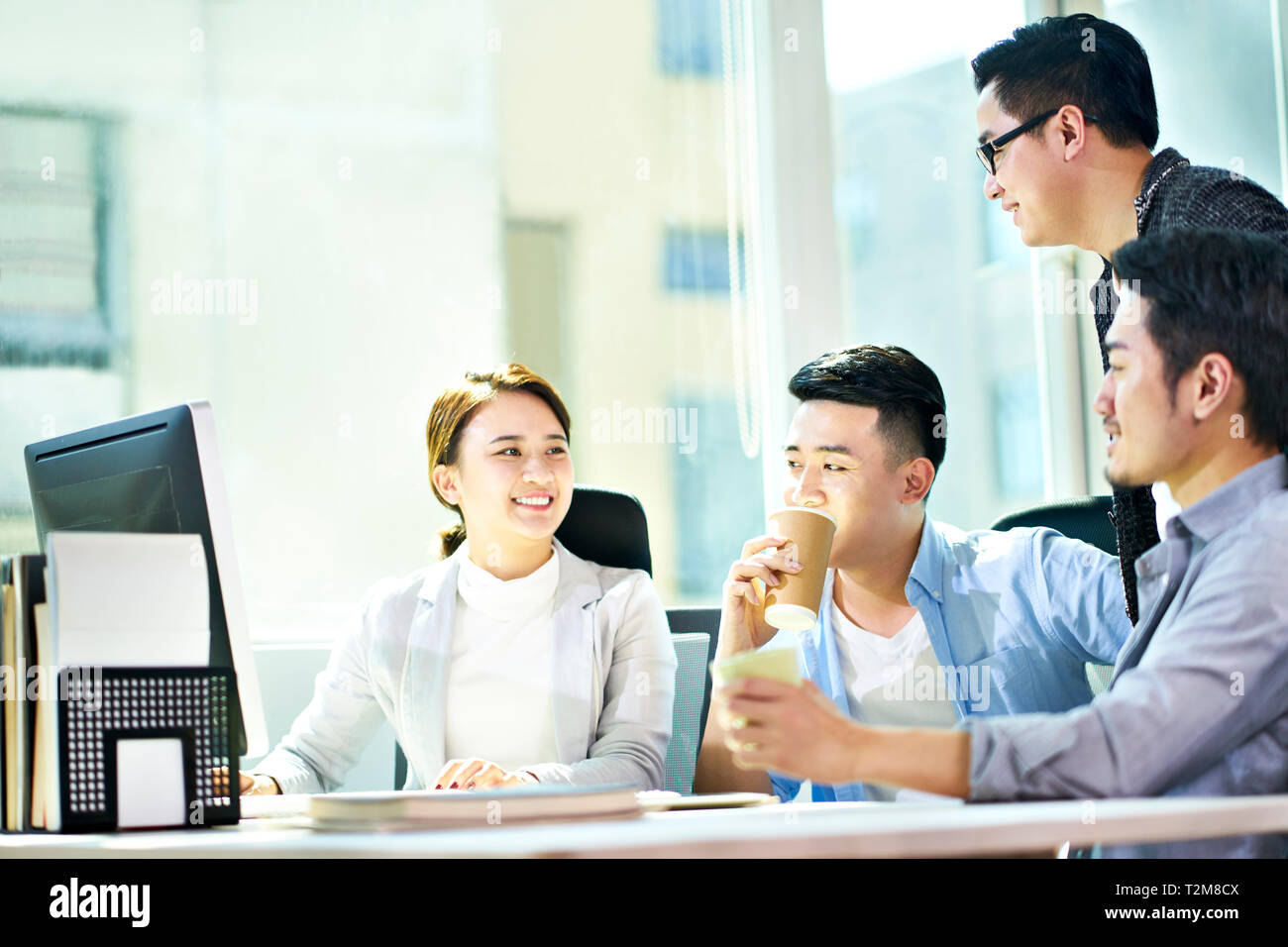 Quattro giovani imprenditori asiatici riuniti a discutere di office business plan utilizzando tablet PC. Foto Stock