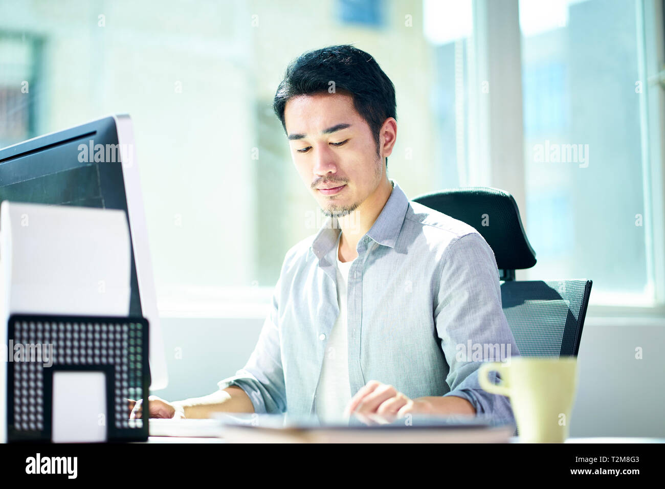 Giovane imprenditore asiatici imprenditore lavora in ufficio con computer desktop. Foto Stock