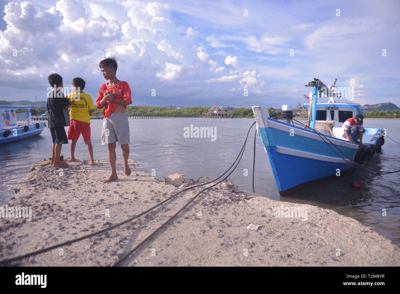 Bambini locali accanto a una barca ancorata sull isola pasaran. Pasaran è un isola bonificata in provincia di Lampung, Indonesia e è il sale del centro di pesce. Si stabilì a gestione internazionale in Lampung Bay, e separata dalla terraferma per circa 100 metri. Foto Stock