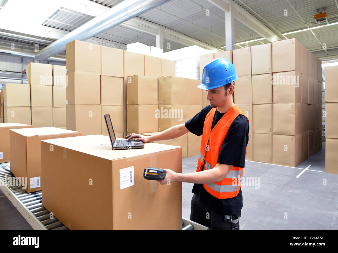 Lavoratore di logistica - uomo scansiona i pacchi di merci e prepara la spedizione in un'azienda department store Foto Stock