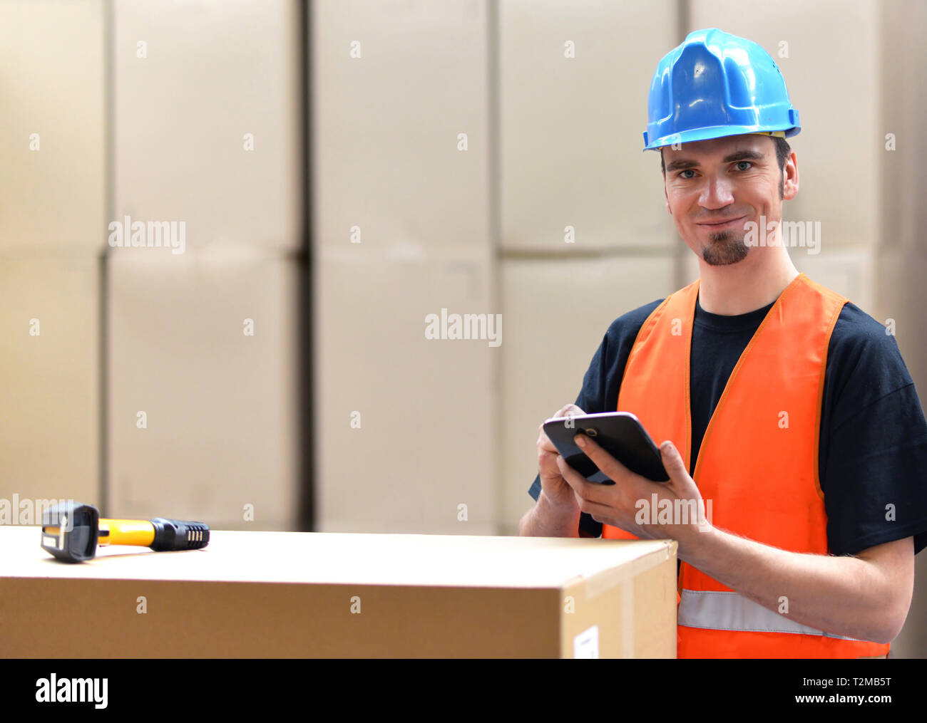Lavoratore di logistica - uomo scansiona i pacchi di merci e prepara la spedizione in un'azienda department store Foto Stock