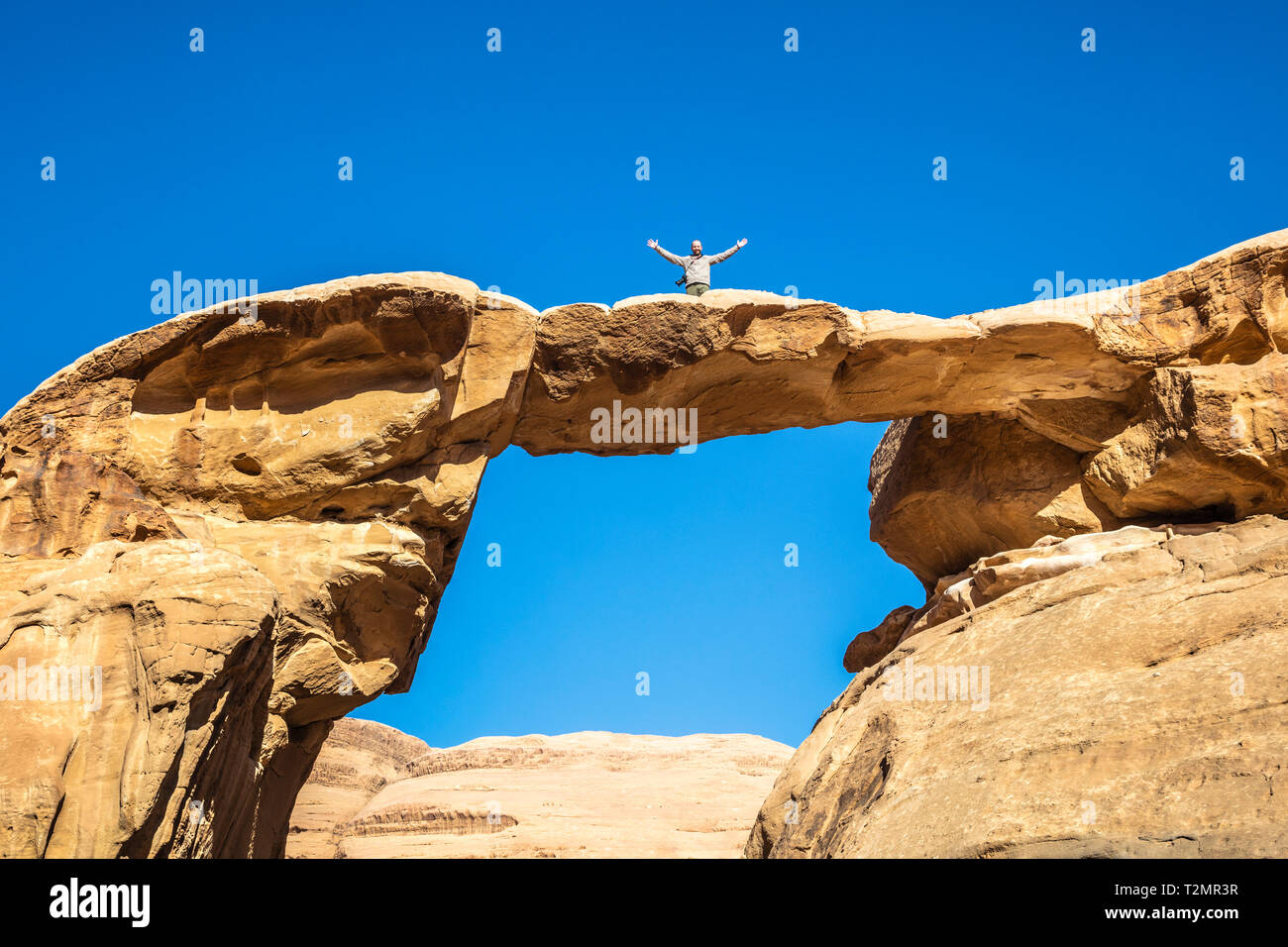 Famoso Um Frouth arch rock, situato nel Wadi Rum desert in Giordania. Fotografo di viaggiatori con le braccia aperte in posa per una foto souvenir. la felicità di essere Foto Stock