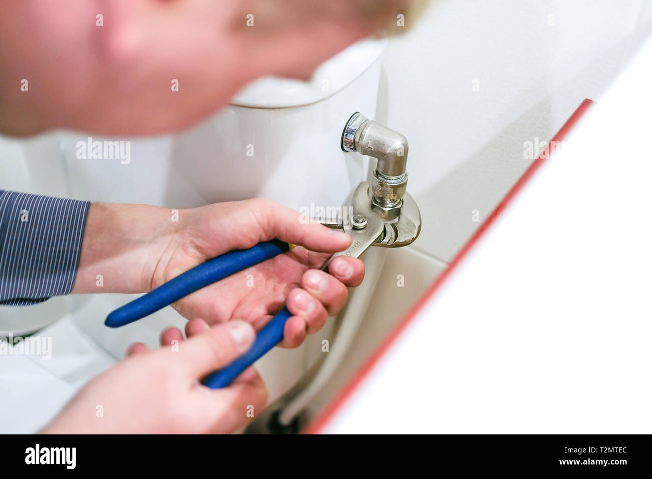 Lavoratore sanitario esegue la riparazione della tazza di gabinetto, tubo rotto Foto Stock