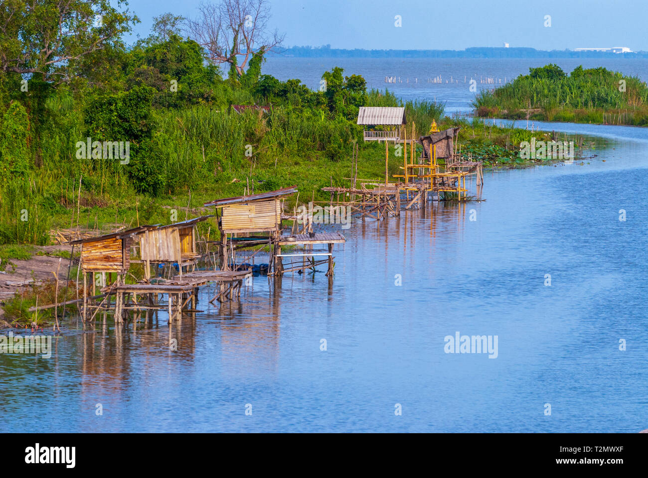 Capanne di pescatori e reti da pesca lungo il fiume, Thailandia Foto Stock