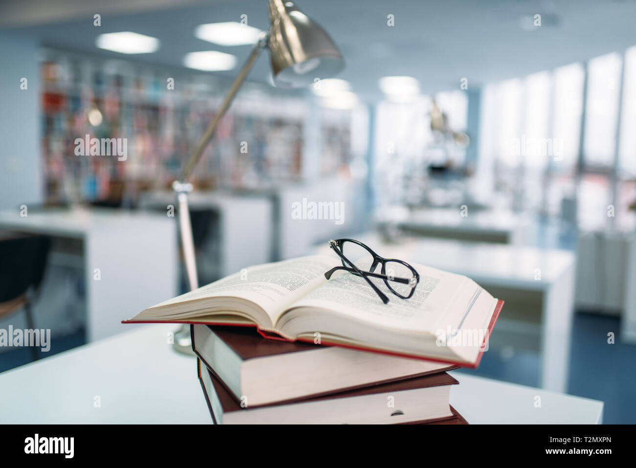 Pila di libri e i bicchieri sul tavolo della biblioteca universitaria, nessuno. Conoscenza depositario, il concetto di istruzione Foto Stock