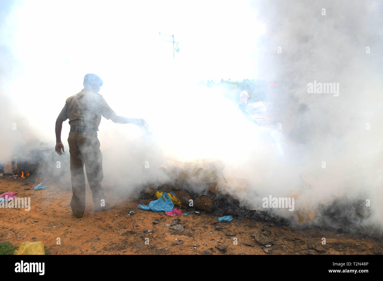 Agartala. 3 apr, 2019. Un poliziotto indiano getta blocchi di confiscare la marijuana in incendio in una discarica nella periferia di Agartala, capitale del nord-est stato di Tripura, India, il 3 aprile 2019. Credito: Xinhua/Alamy Live News Foto Stock
