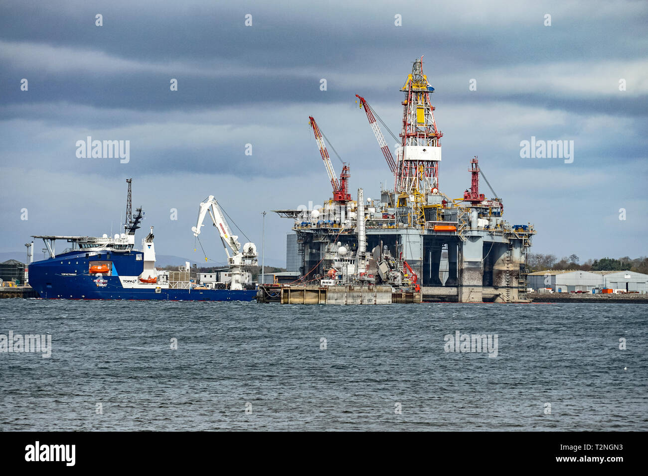 Energia globale a Nigg parco energetico Porto di Nigg Highland Scozia UK visto da Cromarty sul Black Isle con rig e nave Topaz Tiamat Foto Stock