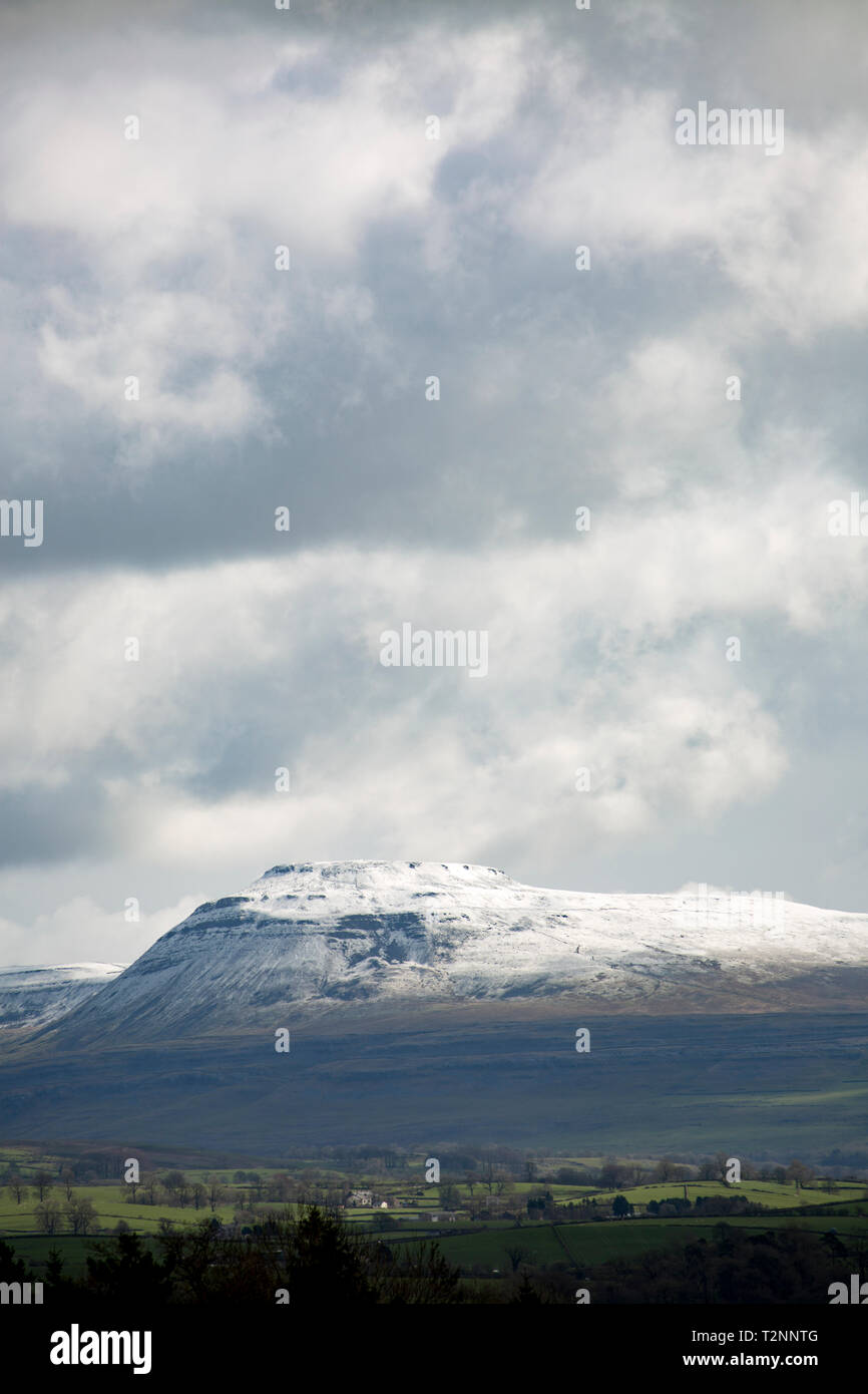 Ingleborough montagna con una copertura di neve sotto le nuvole il 2 aprile 2019. Ingleborough è popolare con hill walkers e fa parte dei tre picchi di Foto Stock