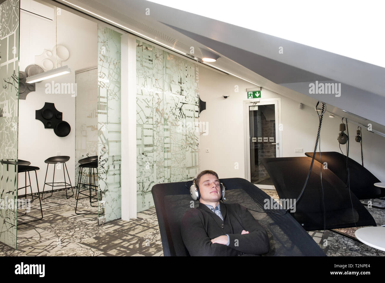 Un giovane uomo bianco si rilassa ascoltando musica in un ambiente aziendale. Foto Stock